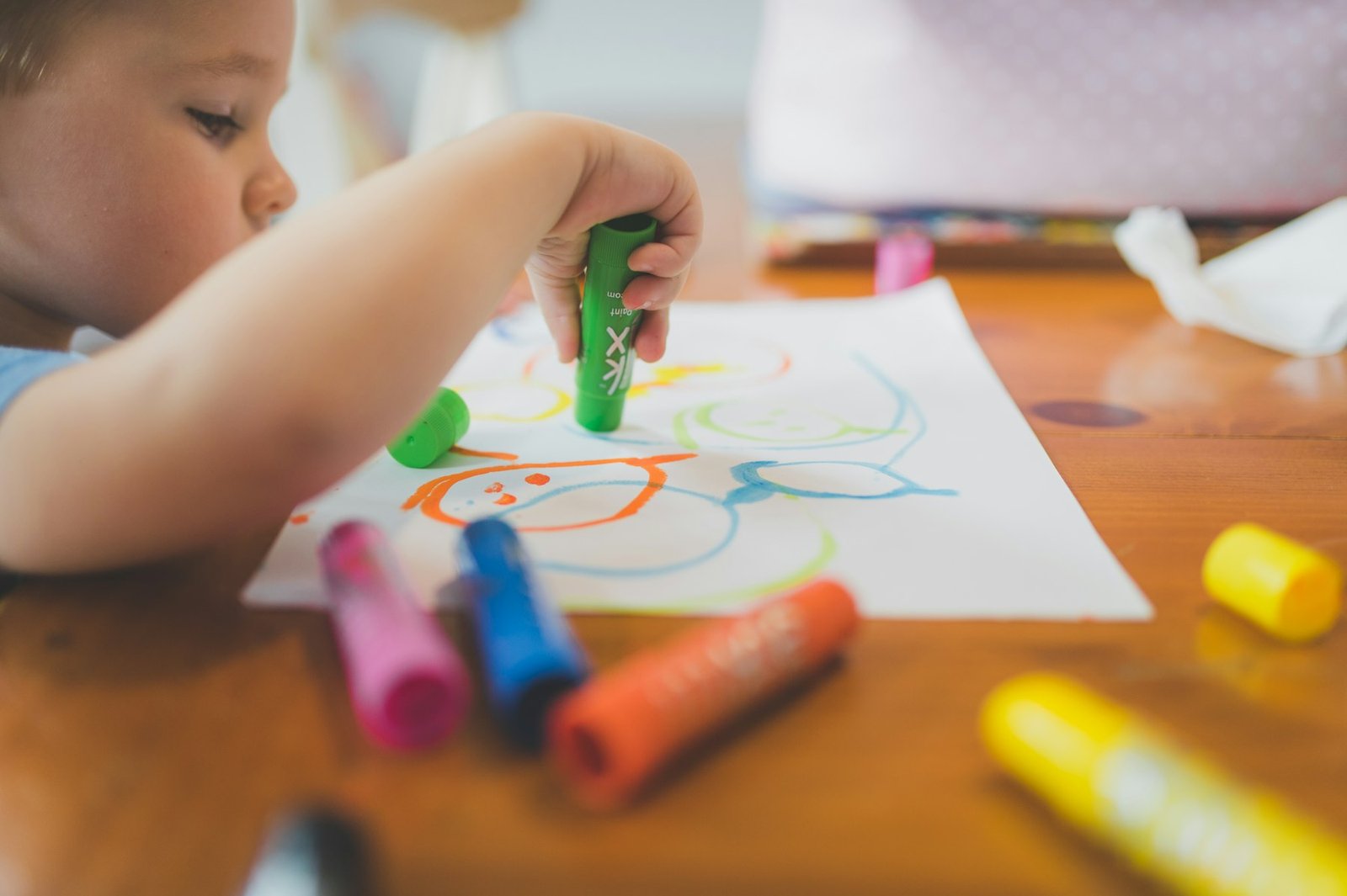 Manos de un niño dibujando con ceras de colores