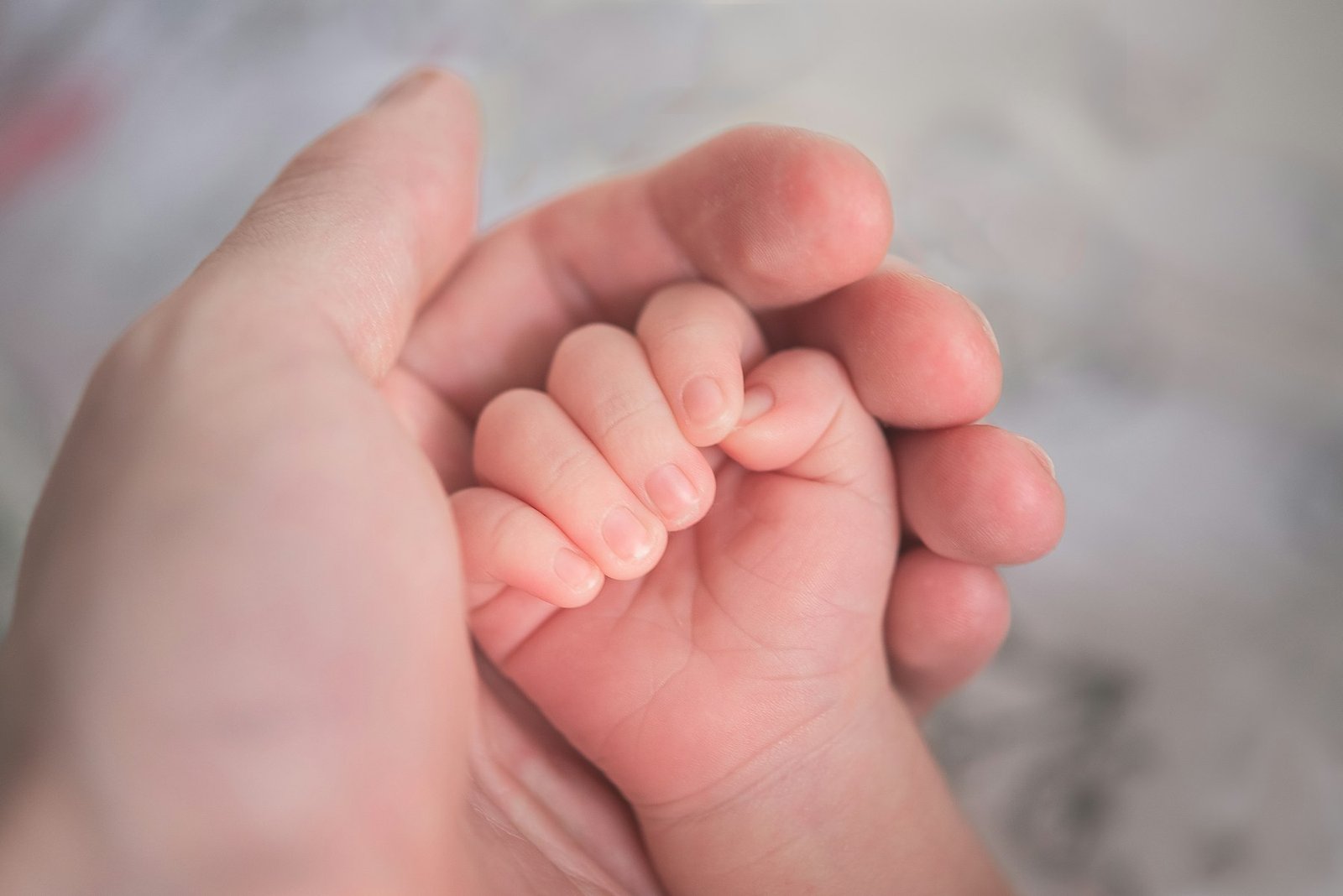 Mano de un bebé agarrando la mano de su madre