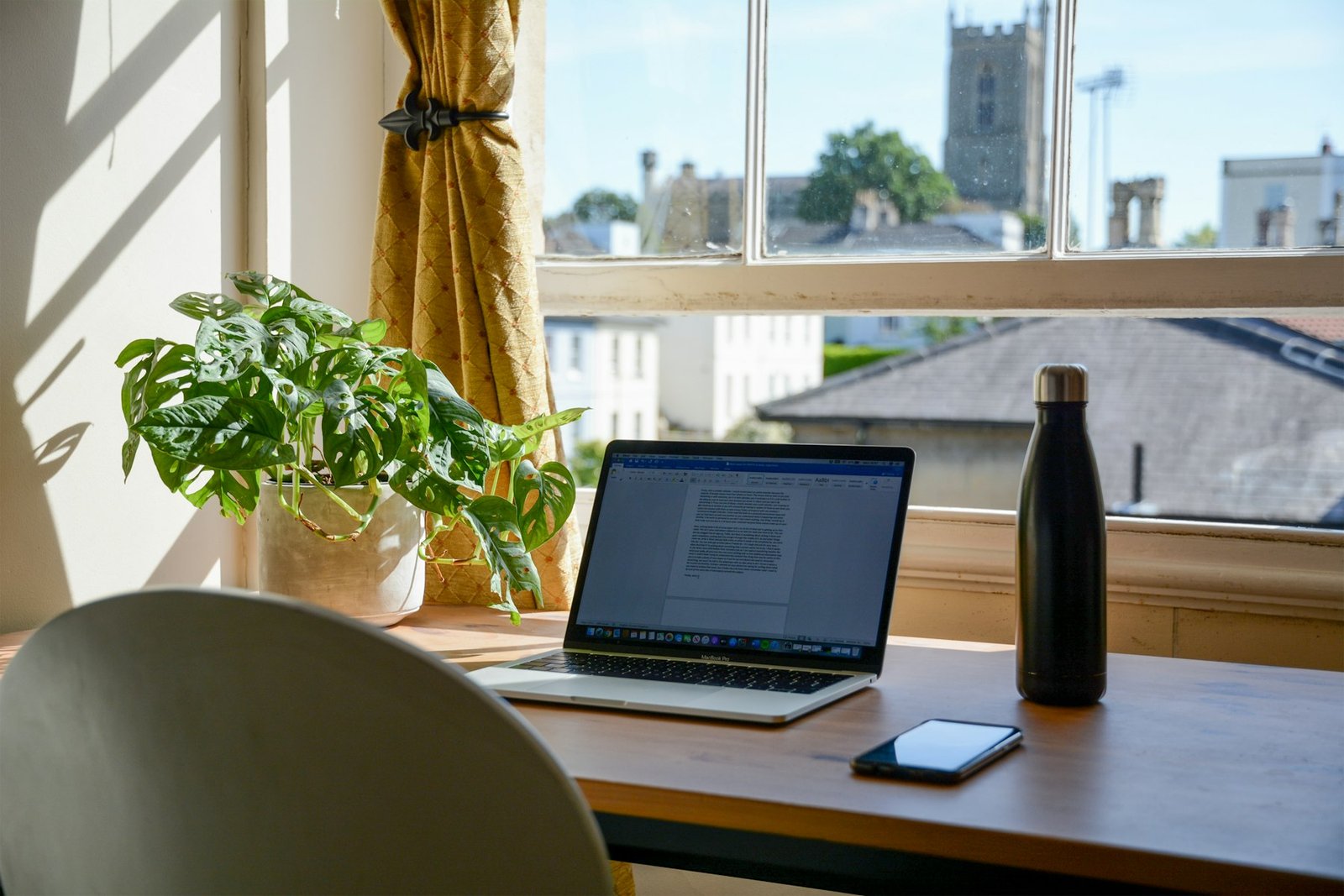 Portátil en una mesa junto a la ventana y plantas